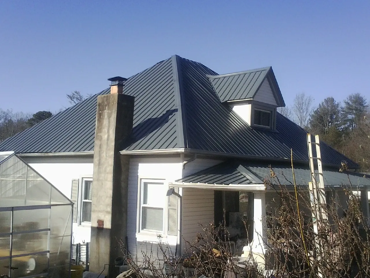 Dark blue standing seam metal roof on a white farmhouse with dormer — Slate & Tile Roof Repair by Roofing Brothers in Kenosha