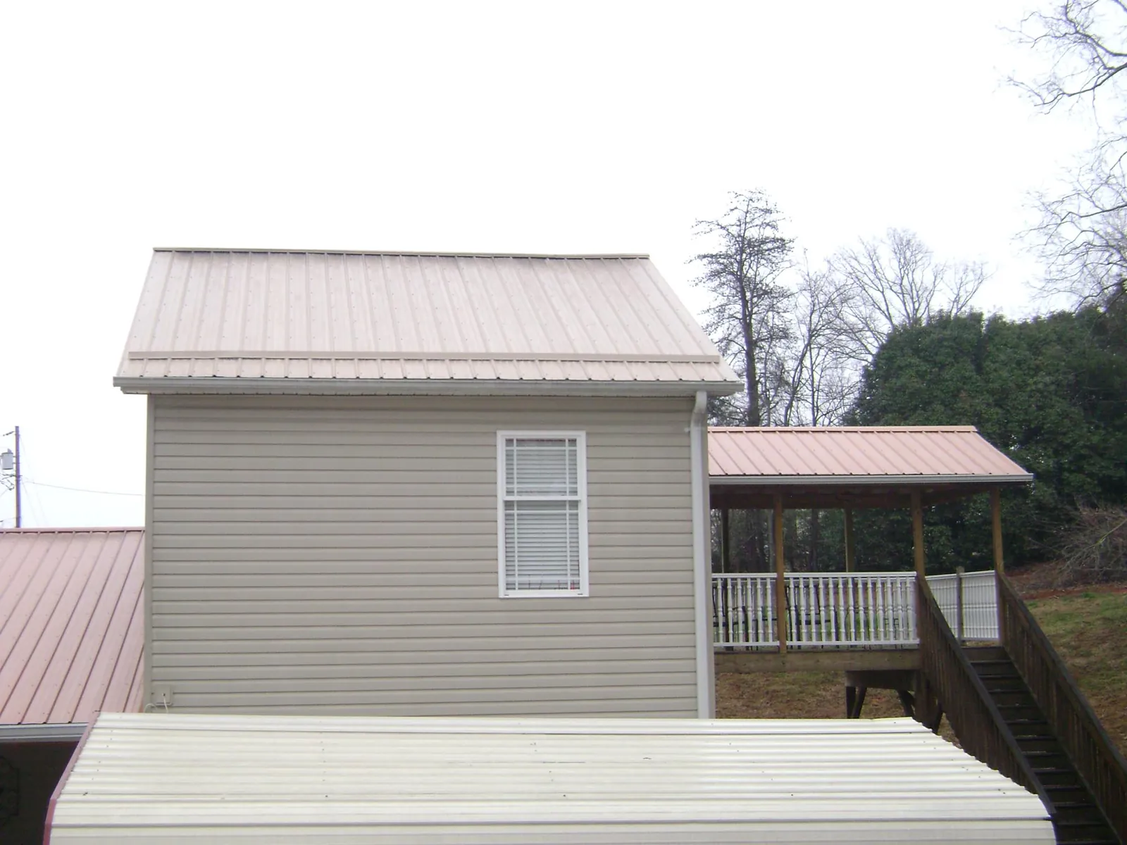 Tan metal roofs on a two story addition and attached porch, from a Roof Replacement job in Kenosha