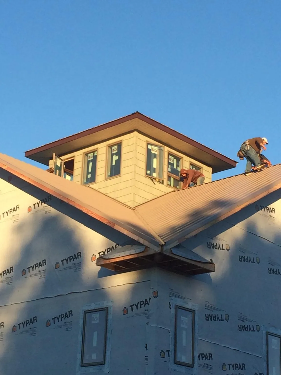 Roofers working around a rooftop cupola on a new metal roof at sunset — Roof Waterproofing in Kenosha by Roofing Brothers